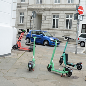 Auf dem Bild sind vier E-Scooter zu sehen an einer Straßenecke.