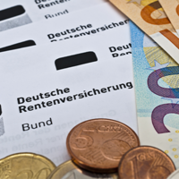 Das Bild zeigt mehrere Dokumente der Deutschen Rentenversicherung, die teilweise von Euro-Banknoten und Münzen bedeckt sind. Die Banknoten umfassen verschiedene Stückelungen, darunter 20- und 50-Euro-Scheine. Im Vordergrund sind auch einige Euro-Münzen zu sehen. Die Dokumente tragen den Aufdruck "Deutsche Rentenversicherung Bund".