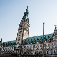 Das Bild zeigt das Hamburger Rathaus. Der Himmel im Hintergrund ist klar und blau, was das Gebäude eindrucksvoll erscheinen lässt. Das Bild ist aus der Froschperspektive gemacht.