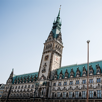 Das Bild zeigt das Hamburger Rathaus. Der Himmel im Hintergrund ist klar und blau, was das Gebäude eindrucksvoll erscheinen lässt. Das Bild ist aus der Froschperspektive gemacht.