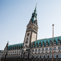 Das Bild zeigt das Hamburger Rathaus. Der Himmel im Hintergrund ist klar und blau, was das Gebäude eindrucksvoll erscheinen lässt. Das Bild ist aus der Froschperspektive gemacht.