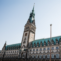 Das Bild zeigt das Hamburger Rathaus. Der Himmel im Hintergrund ist klar und blau, was das Gebäude eindrucksvoll erscheinen lässt. Das Bild ist aus der Froschperspektive gemacht.