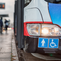 Auf dem Bild hält grade ein Bus des ÖPNV an einer Bushaltestellt. Abgebildert sich die Symbole für Senioren und Rollstuhlfahrer.