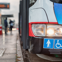 Auf dem Bild hält grade ein Bus des ÖPNV an einer Bushaltestellt. Abgebildert sich die Symbole für Senioren und Rollstuhlfahrer.