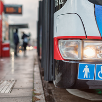 Auf dem Bild hält grade ein Bus des ÖPNV an einer Bushaltestellt. Abgebildert sich die Symbole für Senioren und Rollstuhlfahrer.