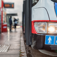 Auf dem Bild hält grade ein Bus des ÖPNV an einer Bushaltestellt. Abgebildert sich die Symbole für Senioren und Rollstuhlfahrer.