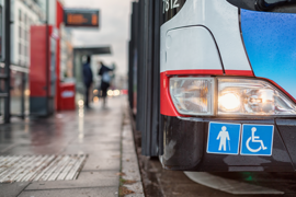 Auf dem Bild hält grade ein Bus des ÖPNV an einer Bushaltestellt. Abgebildert sich die Symbole für Senioren und Rollstuhlfahrer.