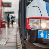 Auf dem Bild hält grade ein Bus des ÖPNV an einer Bushaltestellt. Abgebildert sich die Symbole für Senioren und Rollstuhlfahrer.