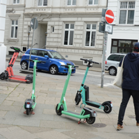 Auf dem Bild sind vier E-Scooter zu sehen an einer Straßenecke.