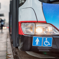 Auf dem Bild hält grade ein Bus des ÖPNV an einer Bushaltestellt. Abgebildert sich die Symbole für Senioren und Rollstuhlfahrer.