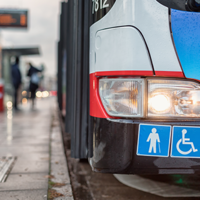 Auf dem Bild hält grade ein Bus des ÖPNV an einer Bushaltestellt. Abgebildert sich die Symbole für Senioren und Rollstuhlfahrer.