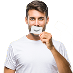 Ein junger Mann mit braunen Haaren und Bart steht vor einem gelben Hintergrund. Er trägt ein weißes T-Shirt. Mit einer Hand hält er ein kleines Stück Papier vor seinen Mund, auf dem ein gezeichnetes Lächeln zu sehen ist. 