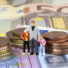 Das Bild zeigt drei Miniaturfiguren, die eine Familie darstellen, bestehend aus einem Erwachsenen und zwei Kindern. Sie stehen auf einem Haufen von Euro-Münzen und -Scheinen. Die Münzen sind in verschiedenen Größen gestapelt, und die Scheine sind im Hintergrund sichtbar.
