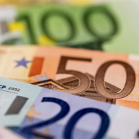 Das Bild zeigt eine Nahaufnahme von mehreren Euro-Banknoten, die teilweise übereinander liegen. Zu sehen sind Banknoten im Wert von 100, 50 und 20 Euro. 