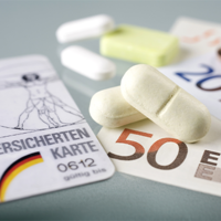 Auf dem Bild sind eine Krankenversicherungskarte, mehrere Euro-Banknoten und -Münzen sowie einige Tabletten zu sehen. Die Krankenversicherungskarte liegt links im Vordergrund, während die Banknoten und Münzen rechts daneben platziert sind. Die Tabletten befinden sich in der Mitte des Bildes.