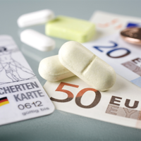 Auf dem Bild sind eine Krankenversicherungskarte, mehrere Euro-Banknoten und -Münzen sowie einige Tabletten zu sehen. Die Krankenversicherungskarte liegt links im Vordergrund, während die Banknoten und Münzen rechts daneben platziert sind. Die Tabletten befinden sich in der Mitte des Bildes.